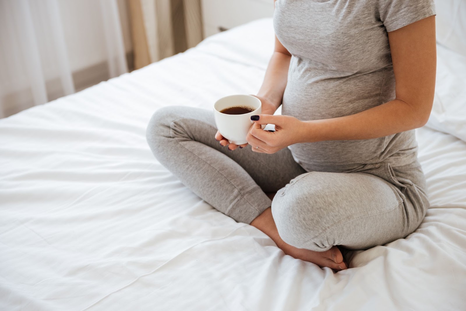 Pregnant woman with cup of coffee.